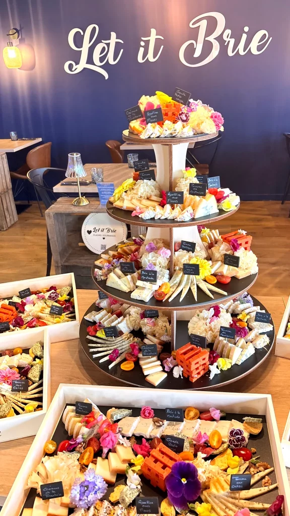Pièce montée de fromages décorée de fleurs fraîches avec plateaux gourmands réalisée par Let it Brie aux Herbiers.