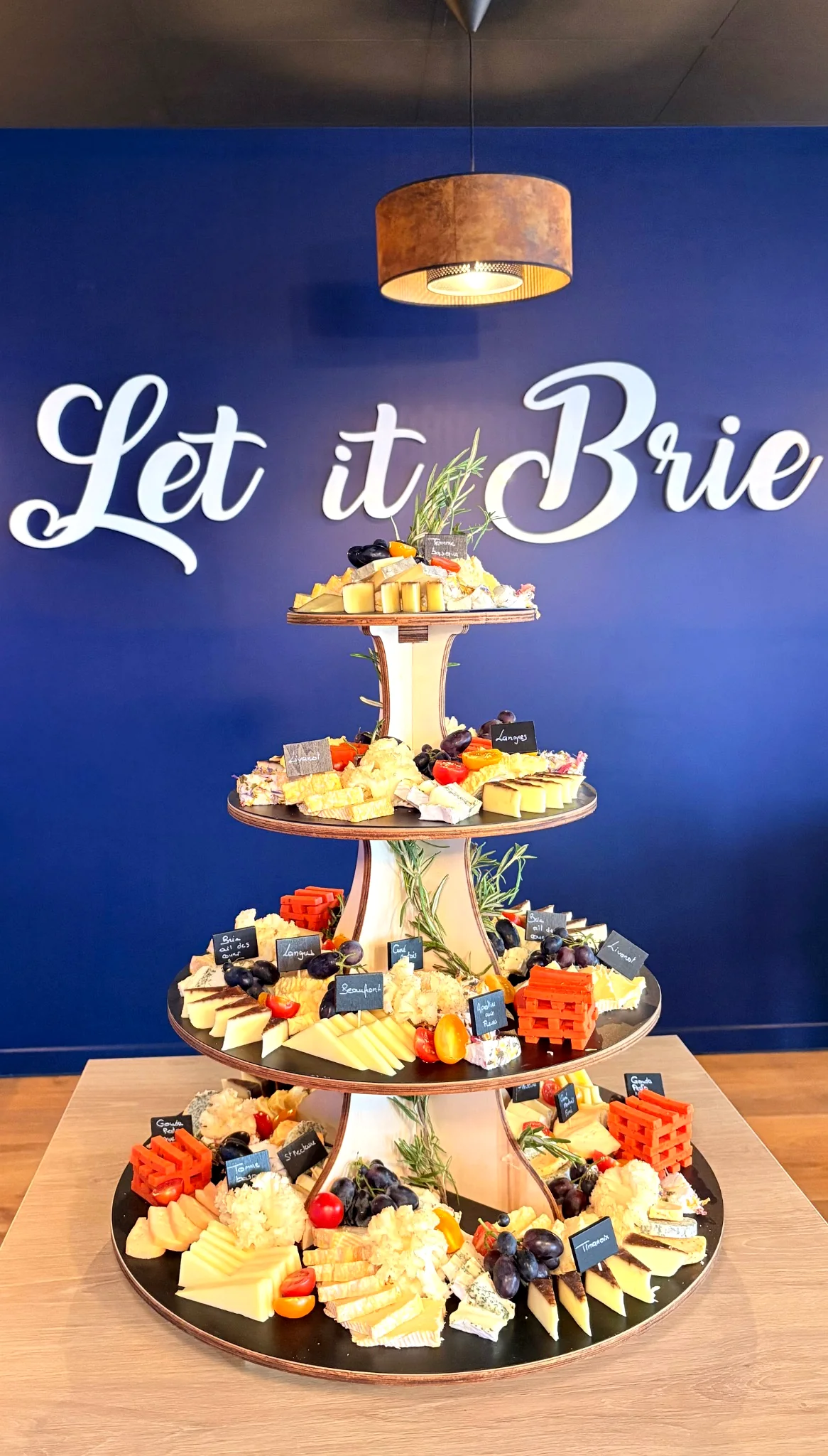 Vue rapprochée d'une pièce montée de fromages décorée de fleurs réalisée par Let it Brie.